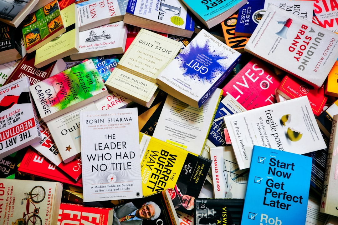 Stack of Business and Self-Help Books with Bold Cover Designs Colorful assortment of business and self-help books spread out on a table, highlighting diverse cover designs, fonts, and styles.